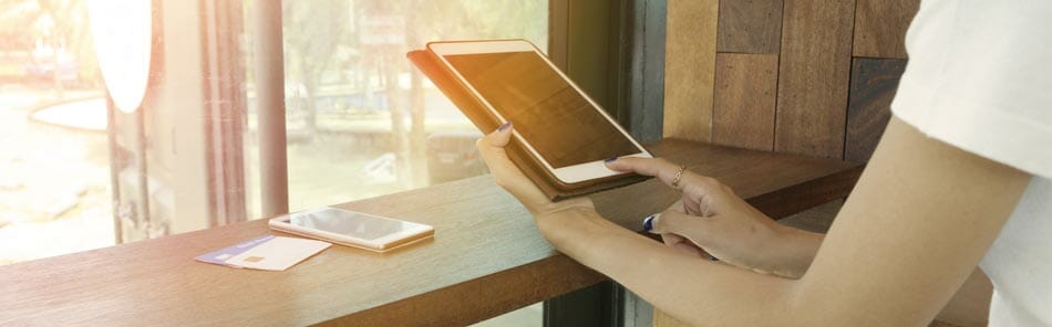 Es ist eine Person abgebildet, die ein Tablet in der Hand hält und eine online Software benutzt um sich einen Blätterkatalog anzusehen.